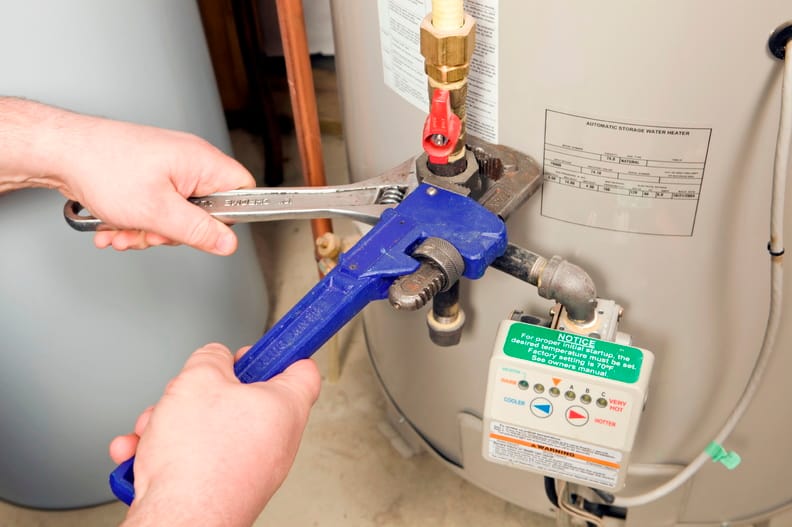 Plumber repairing water heater pipe connection in Sarasota, Florida home