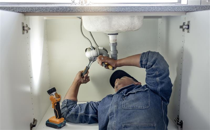Plumber repairing kitchen sink drain pipes in Sarasota, Florida